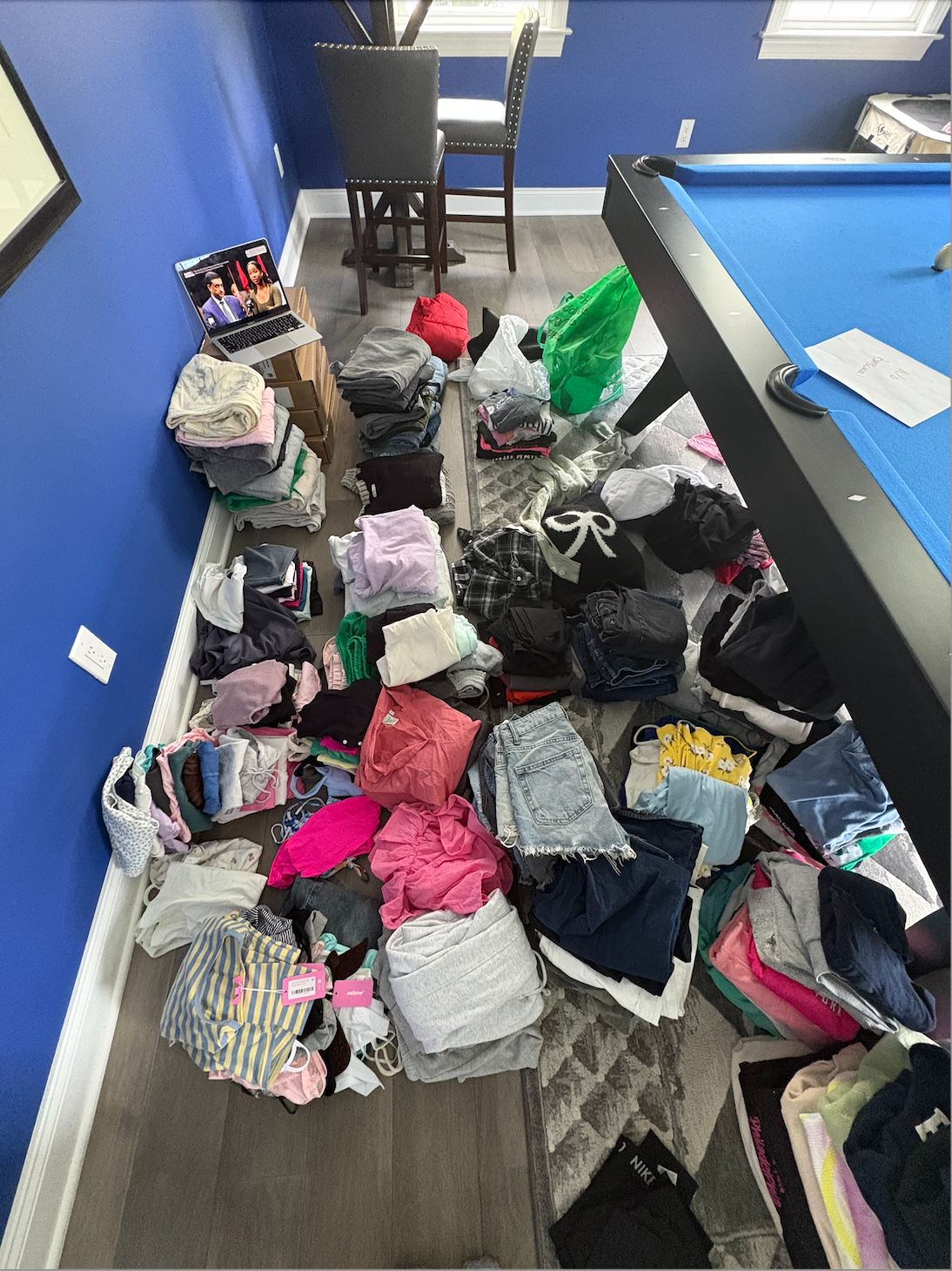 Hundreds of donated clothing items being sorted and folded at home before EmpowerHER Boutique